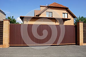 private brown gates and part of a fence made of metal and bricks in the street