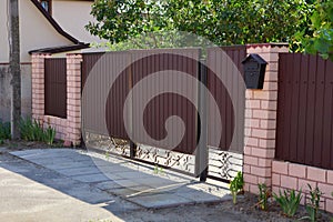Private brown gates and part of a fence made of metal and bricks in the street