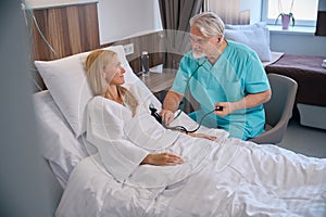 Private clinic doctor examining female patient during morning ward round