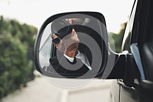 Private detective with camera spying from auto, view through car side mirror