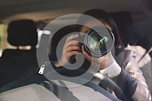 Private detective with camera spying from car