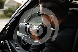 Private detective with camera spying from car