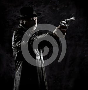 A private detective with a revolver in front of a black backdrop