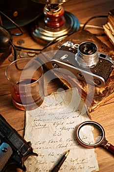 Private detective`s desk, noir still life with a vintage phone, typewriter, lamp, gun and retro photos