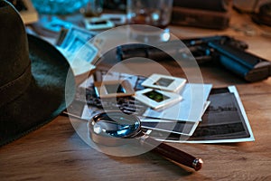 Private detective`s desk, noir still life with a vintage phone, typewriter, lamp, gun and retro photos