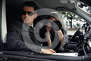 Private detectives with modern camera spying from car