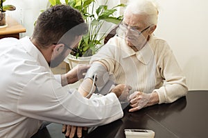 A private doctor`s office. Geriatrician doctor takes the patient and measure her blood pressure. photo