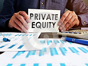 Private equity concept. Manager sitting at the table holds an inscription.