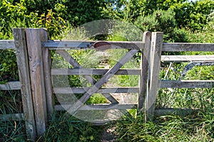 Private farm land fenced off by a large gate with a private keep out sign showing no access to the rural pathway