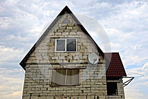 Gray brick house with window and satellite dish on the sky background