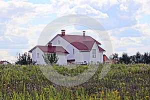 Private house among a green field against a blue sky