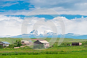 Private houses in the field against the backdrop of beautiful snow-capped mountains