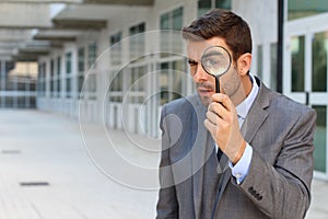 Private investigator looking through a magnifying glass