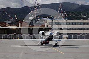 private jet airplane parked at outside in Genoa airport and waiting business persons. Luxury tourism and business travel