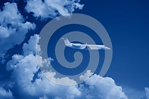private jet business jet flies against backdrop of beautiful clouds on sky toned in trendy Classic Blue color of the Year 2020
