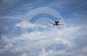 Private jet with landing gear down flying across blue sky with white cirrus clouds
