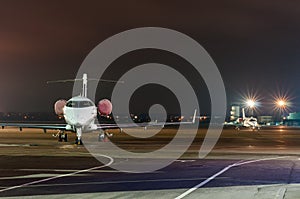 Private jet plane parked in the airport at night. Business travel concept