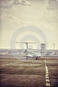 Private jet plane parking at the airport. Private airplane at orange sunset.