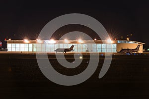 Private jets parked in front of hangar at nigt