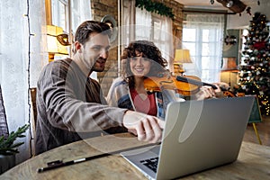 Private male music teacher giving violin lessons to a woman at home