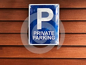 Private parking sign on wooden wall. Blue sign and white color text `Private parking`