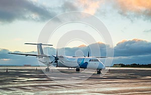 Private propeller-driven airplane parking at the airport with sunset background.