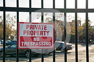 Private property no trespassing sign on black gate in front of parking lot