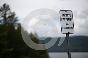 Private Property No Trespassing Sign in front of Forest and Lake