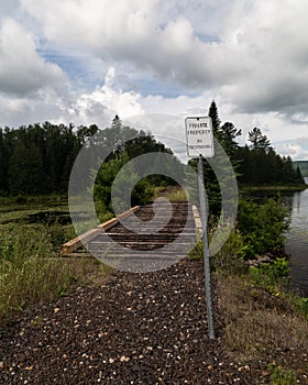 Private Property No Trespassing Sign on Old Train Tracks Rail Path Forest Clouds