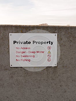 private property sign on grey sea wall barricade no permission