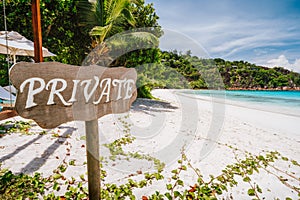 Private sign at tropical sandy beach with blue ocean lagoon in background at Mahe island, Seychelles