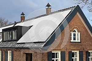 Private solar panels with snow on the roof of old historic and monumental house in the winter.