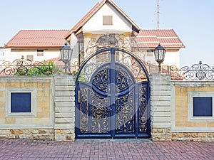 Private villa with stone fence and iron decorative gates with a wrought gilded pattern