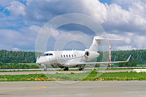 A private white business jet on the runway is preparing for takeoff. Jets of hot exhaust come from jet engines. Jet