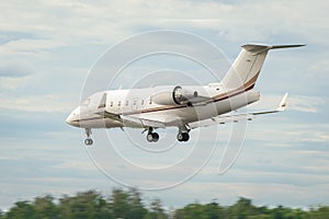 A private white small business jet comes in for a landing. Jet corporate business aviation. Business jet against the