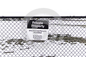 Privet property sing on a metal fence with a blurred snowy field in the background