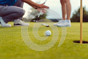 Pro on golf course teaching a woman how to put