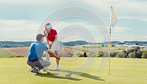 Pro on golf course teaching a woman how to put