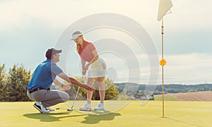 Pro on golf course teaching a woman how to put