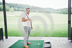 Pro golf player aiming shot with club on course. Male golfer on putting green about to take the shot