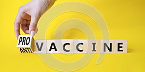 Pro-vaccine vs Anti-vaccine symbol. Doctor hand turns a cube and changes the words Anti-vaccine to Pro-vaccine. Beautiful yellow