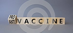 Pro-vaccine vs Anti-vaccine symbol. Turned wooden cubes with words Anti-vaccine vs Pro-vaccine. Beautiful grey background.