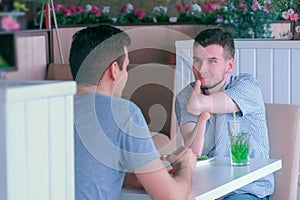 Disabled man with two amputated stump hands meets friend and talks in cafe. photo