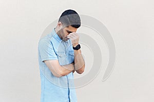 Problem, depression or sickness. Portrait of sad alone handsome young bearded man in blue shirt standing, holding head down and