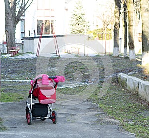 Problem of hopeless barrenness and bringing babies to baby boxes hatch. Lonely pink carriage outdoors without parents