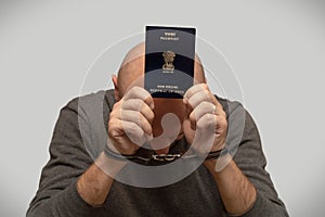 The problem of illegal immigration of refugees from India, an Indian immigrant in handcuffs with a passport in his hands. Illegal