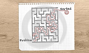 Problem Solving maze, Problem Sorted text, maze solution hand drawn on with red marker on graph paper over wooden desk from