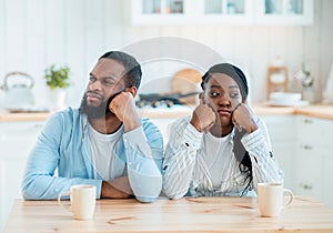 Problems In Relationship. Offended Black Couple Sitting At Table In Kitchen