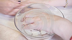 Procedure moisturizing nail, hand lay in the bath with water. Close-up. Manicure beauty salon. manicurist makes the