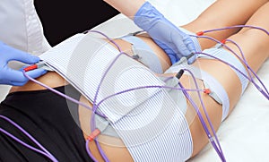 The procedure of myostimulation on the legs and buttocks of a woman in a beauty salon